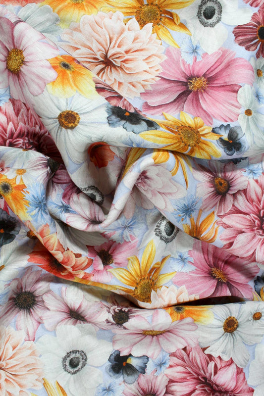 Floral fabric with pink, yellow, orange, blue and white flowers on a pale blue background
