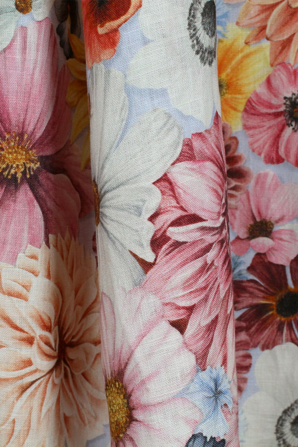 Close up of floral fabric with pink, yellow, orange, blue and white flowers on a pale blue background