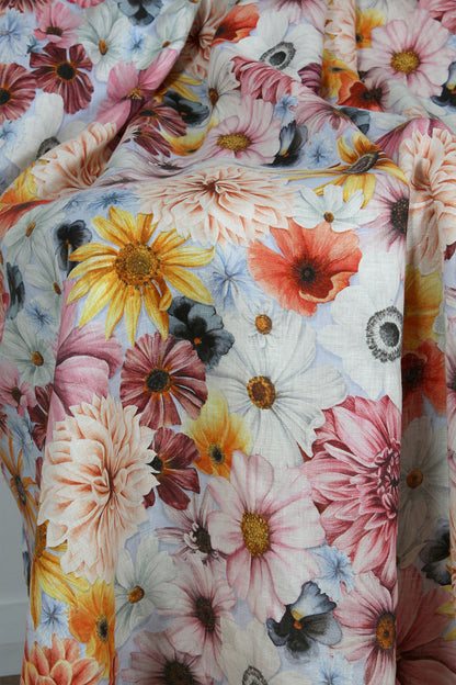 Floral fabric with pink, yellow, orange, blue and white flowers on a pale blue background
