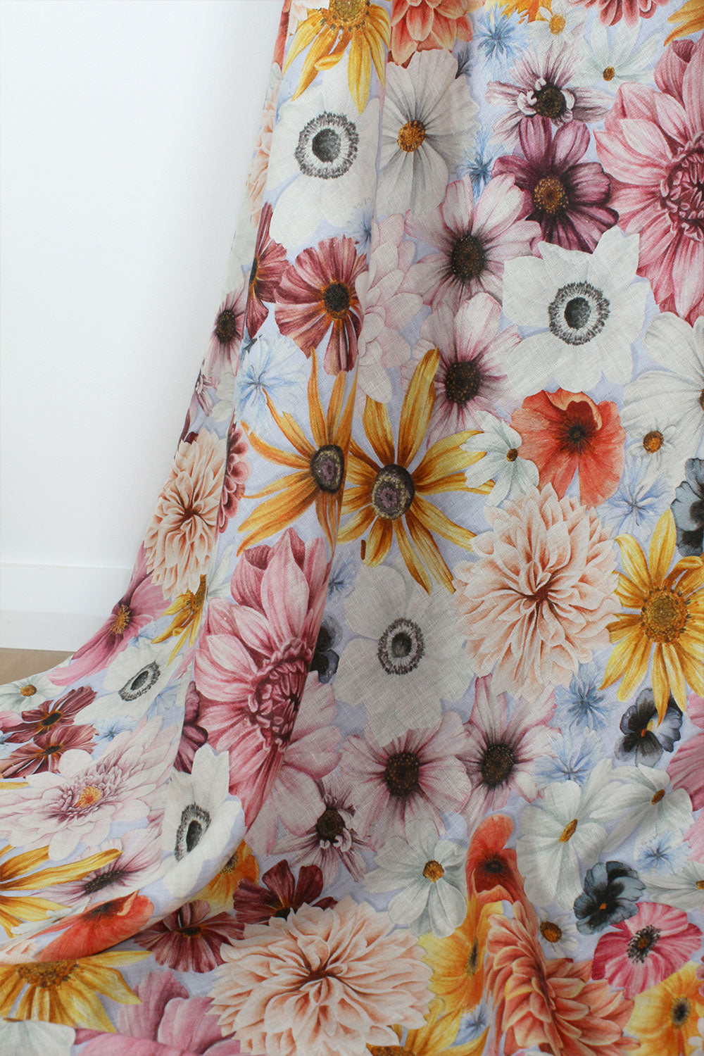 Floral fabric with pink, yellow, orange, blue and white flowers on a pale blue background