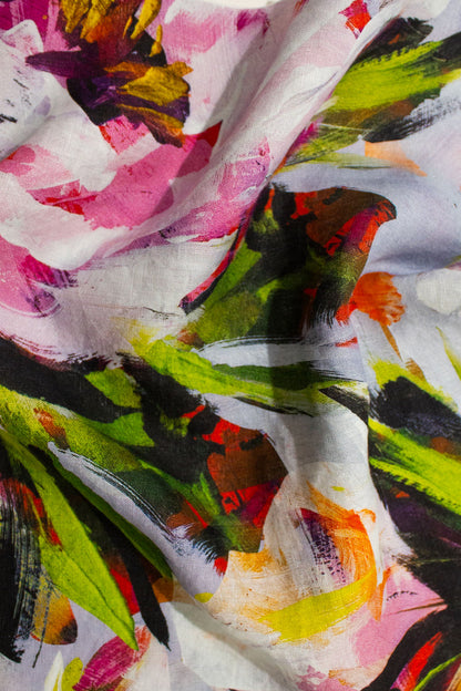 A close-up of a lightweight linen fabric with an abstract floral print, featuring oversized large scale white, pink, green, yellow, and black brushstrokes. @carolynquan.art