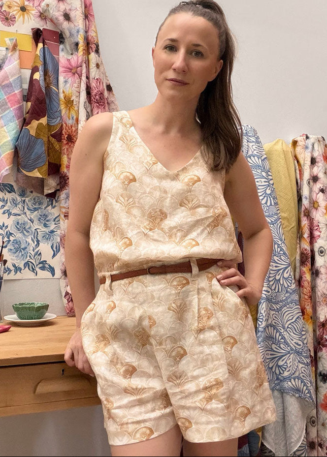 Woman wearing a matching floral top and shorts set in front of colorful fabric swatches.